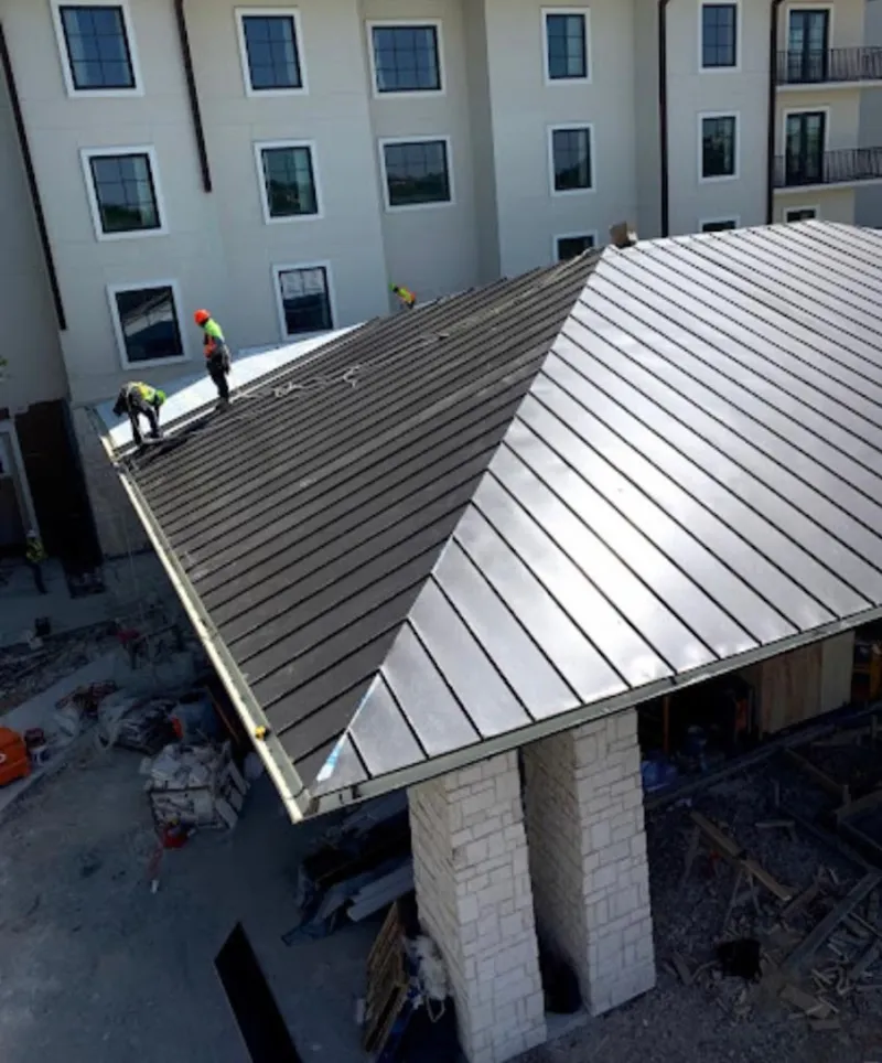 Crew installing standing seam metal roof panels on a commercial project in Helena